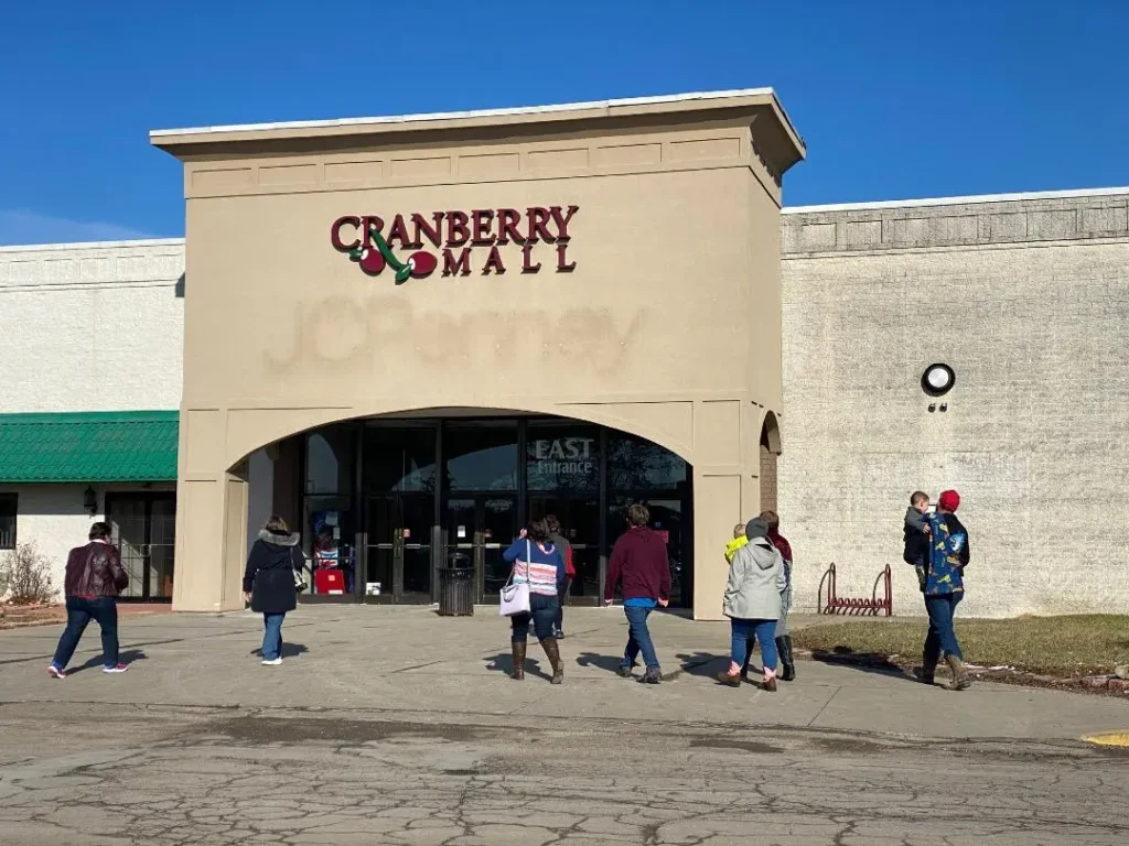 People walking past a cranberry shop in Cranberry Mall, a bustling shopping center.