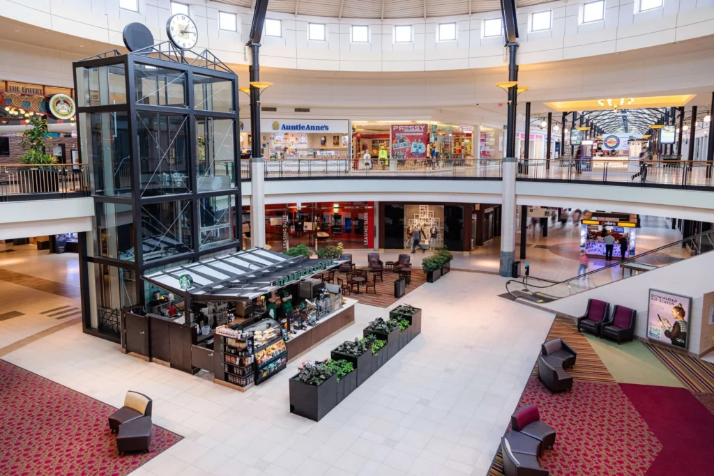 A bustling mall, Dulles Town Center, with a prominent clock tower, teeming with a multitude of people.