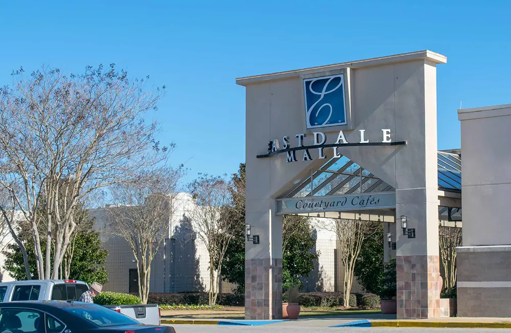 A lively shopping center entrance with parked cars, exuding a vibrant atmosphere that beckons visitors.