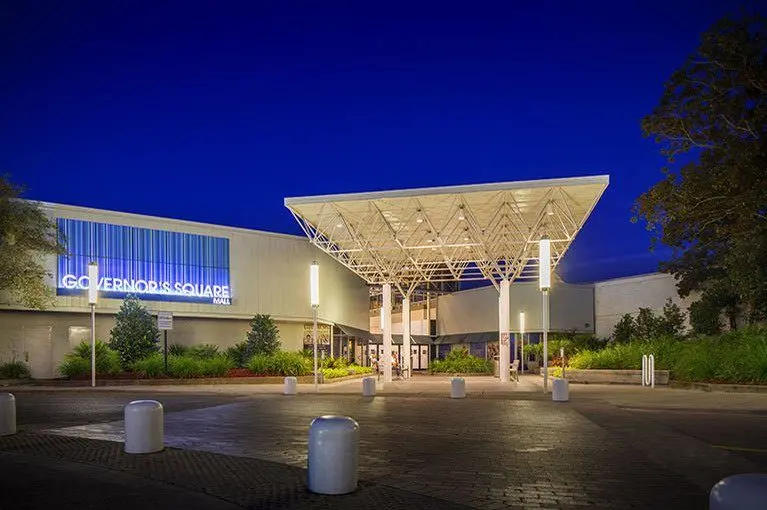 Entrance to Governor’s Square mall at night: illuminated sign and glass doors leading into a bustling shopping center.