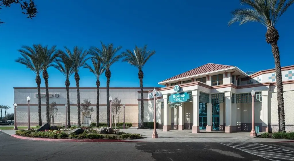 The front entrance to Hanford Mall, adorned with palm trees, welcomes visitors to the shopping center.