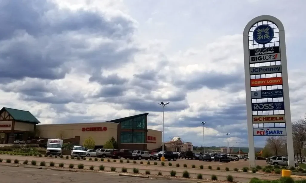 A bustling shopping center, Holiday Village Mall, with numerous stores and a prominent clock.