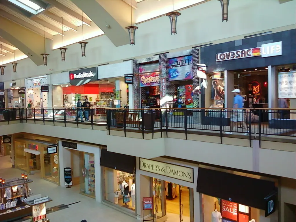 A bustling mall with various stores and people walking around at Jordan Creek Town Center.