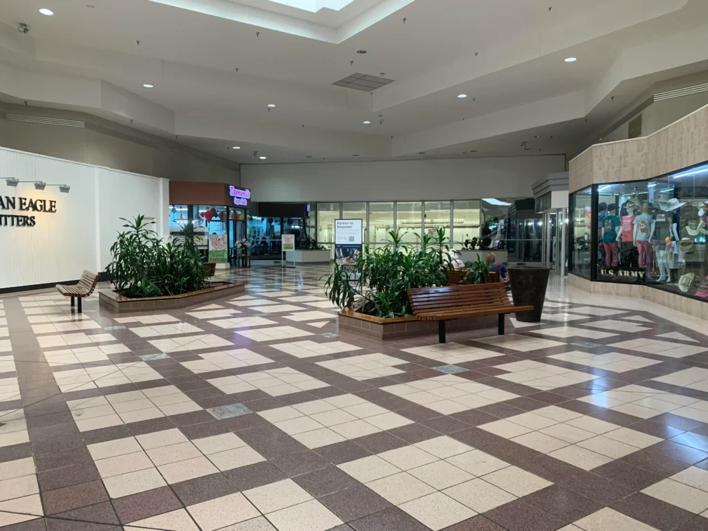 Exterior of Lakeland Square Mall with a large glass window showcasing various stores and shoppers.