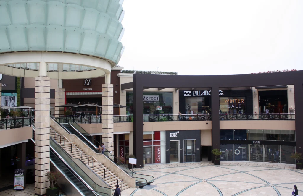 Exterior view of Lima Mall with various stores and shoppers walking around.