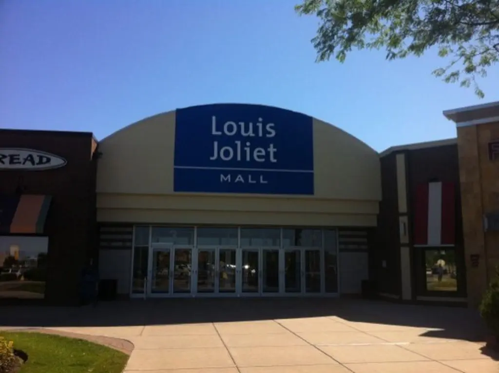 Exterior of Louis Joliet Mall store illuminated at night.