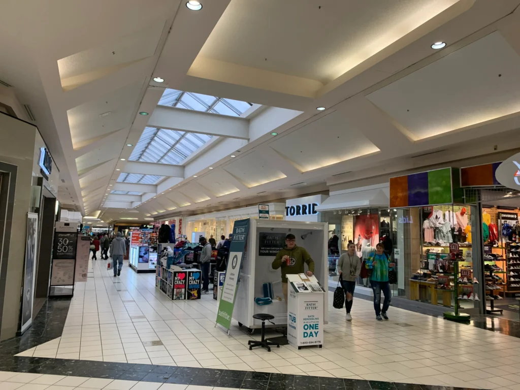 Interior of Morgantown Mall with various stores and shoppers walking around.