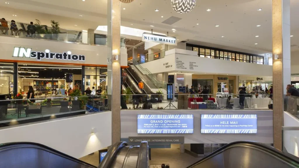 A spacious shopping mall, Pearlridge Center, with a grand ceiling providing ample room for shoppers and a pleasant ambiance.