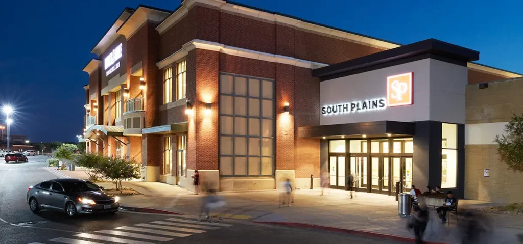 Illuminated building with a wide store front at night, situated at South Plains Mall.