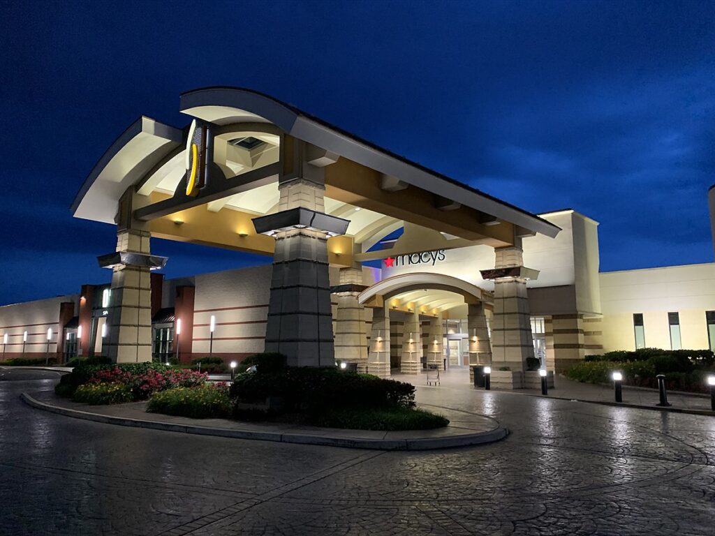 A shopping center hotel's entrance at night, radiating a vibrant ambiance and inviting allure.
