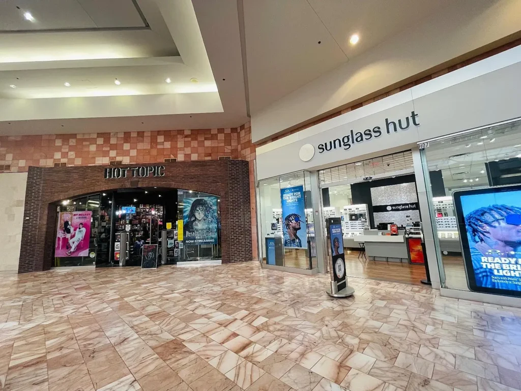 Exterior view of Sunland Mall Shopping Center with palm trees and people walking in front.