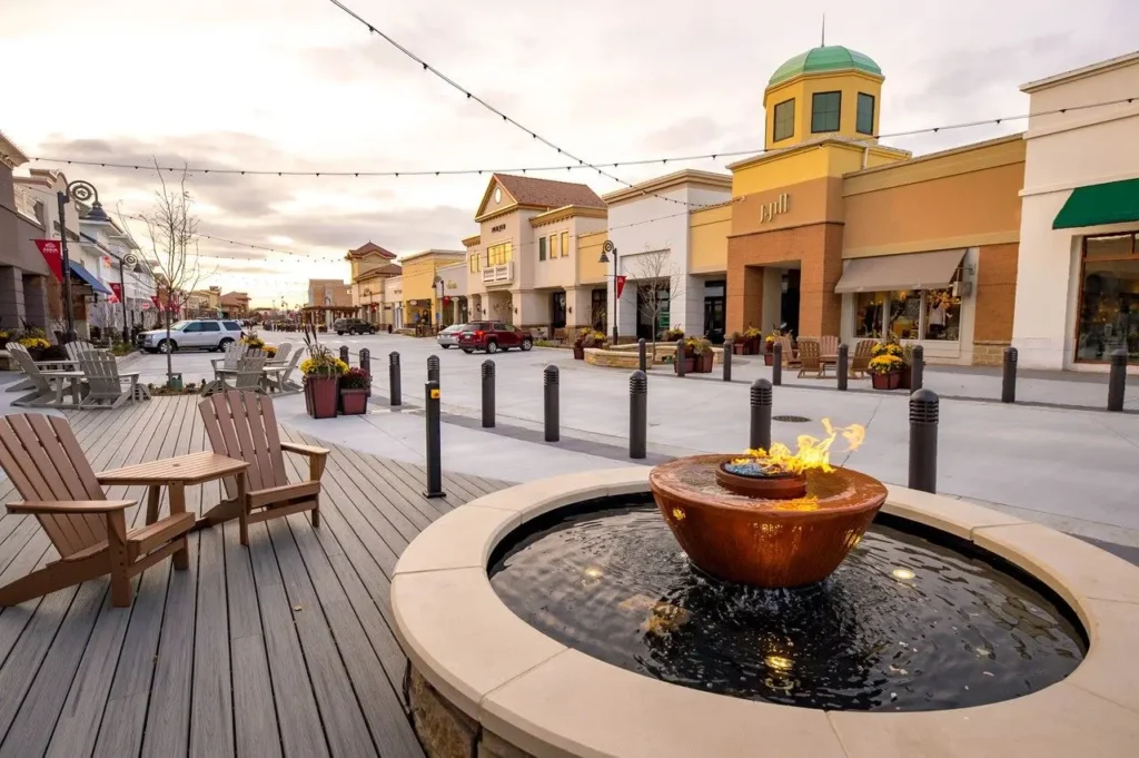 Exterior of The Shoppes at Arbor Lakes with colorful storefronts and people walking around.