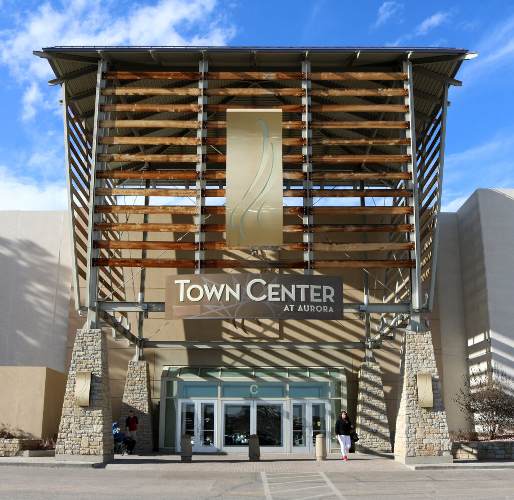 The front of a massive shopping mall, buzzing with activity and marked by construction cones, exuding a vibrant atmosphere.