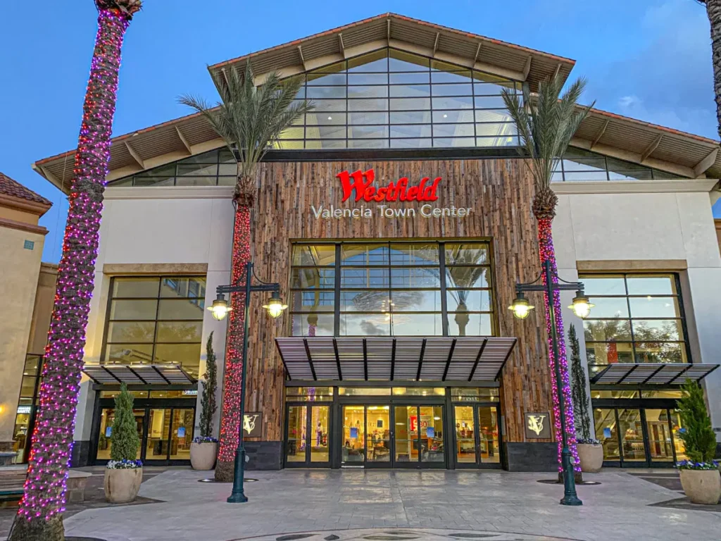 A palm tree-lined Valencia Town Center with a grand building standing tall.