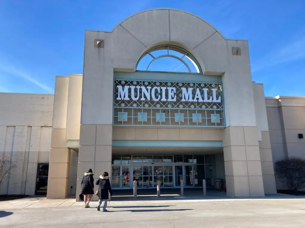 A group of people walking in front of a shopping mall.