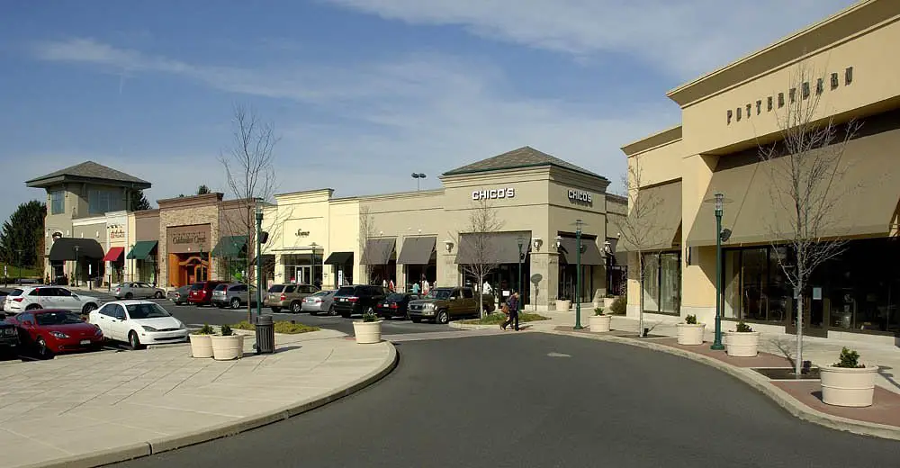 Experience the lively atmosphere of a shopping center as cars fill the streets on both sides. The mall entrance awaits, ready for your shopping adventure!