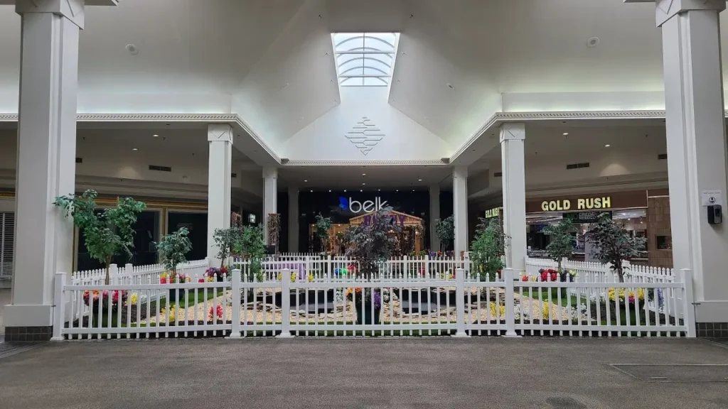 Interior of mall with white fence and flowers.