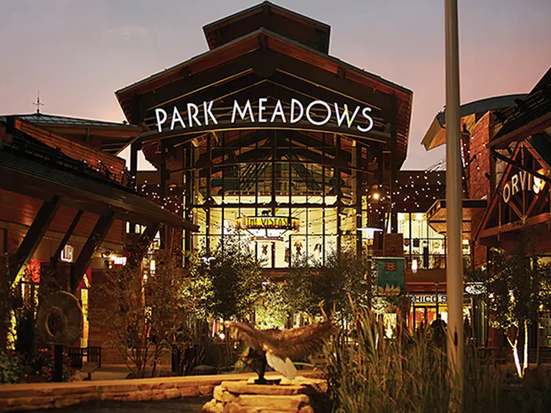 Exterior view of Park Meadows Mall with various stores and shoppers walking around.