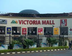 Crowded shopping mall with colorful signs, benches, and people browsing through shops.