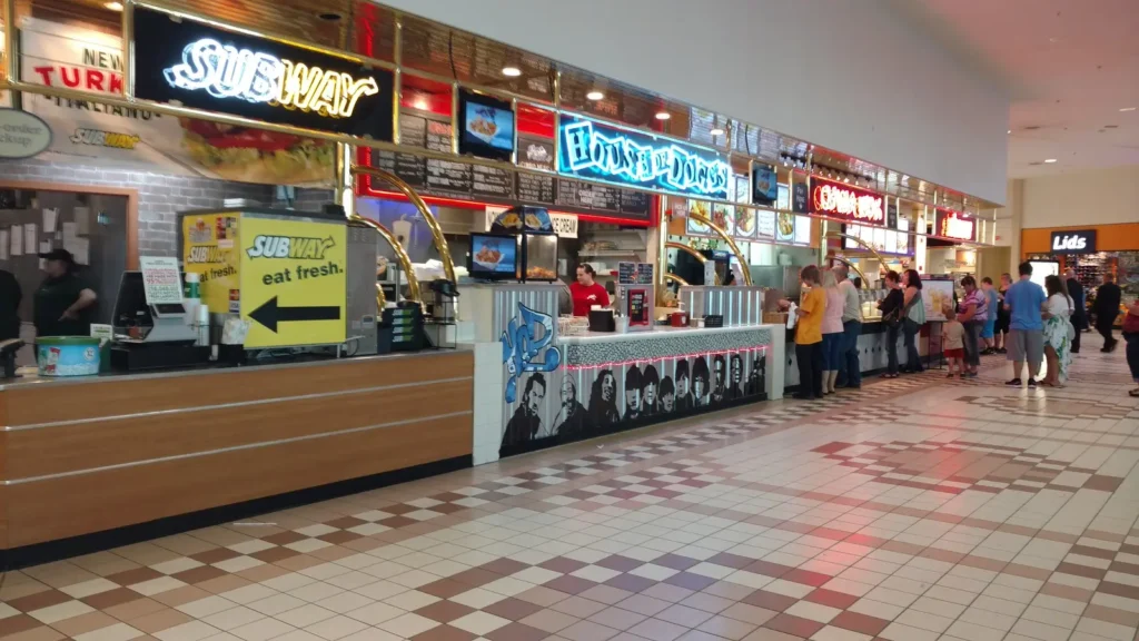 A bustling food court filled with a diverse crowd enjoying a variety of cuisines and socializing.