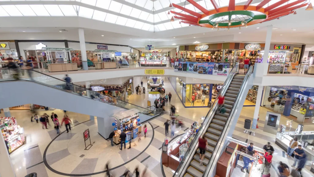 Exterior of PlazAmericas Mall with colorful banners and palm trees in the background.