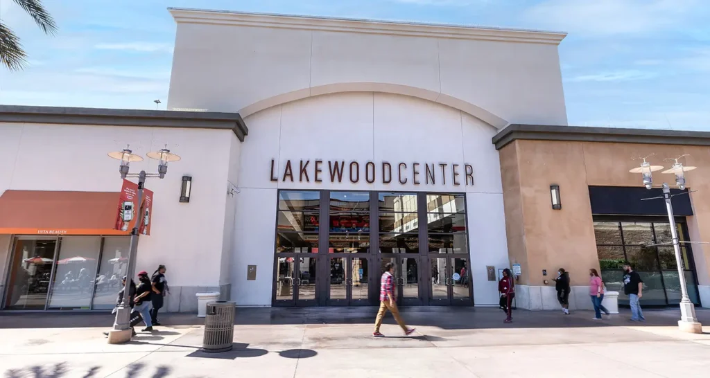 A shopping center surrounded by palm trees and a spacious parking lot.