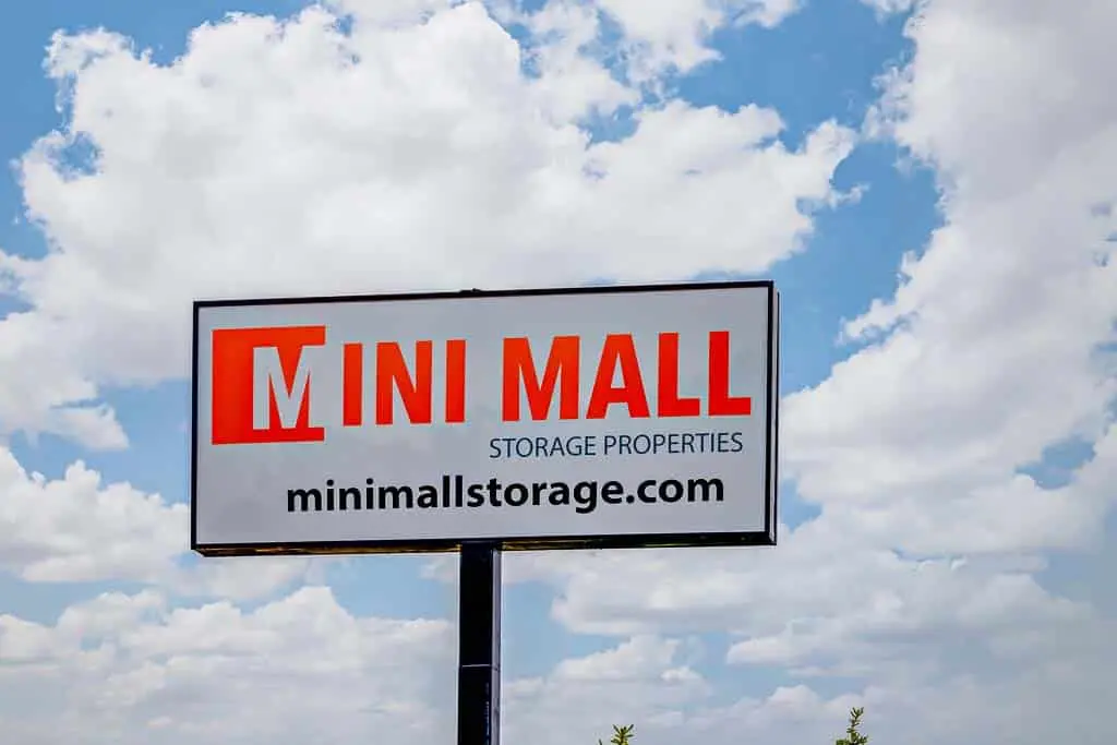 Mini Mall Storage building with colorful sign, rows of storage units, and people loading items.