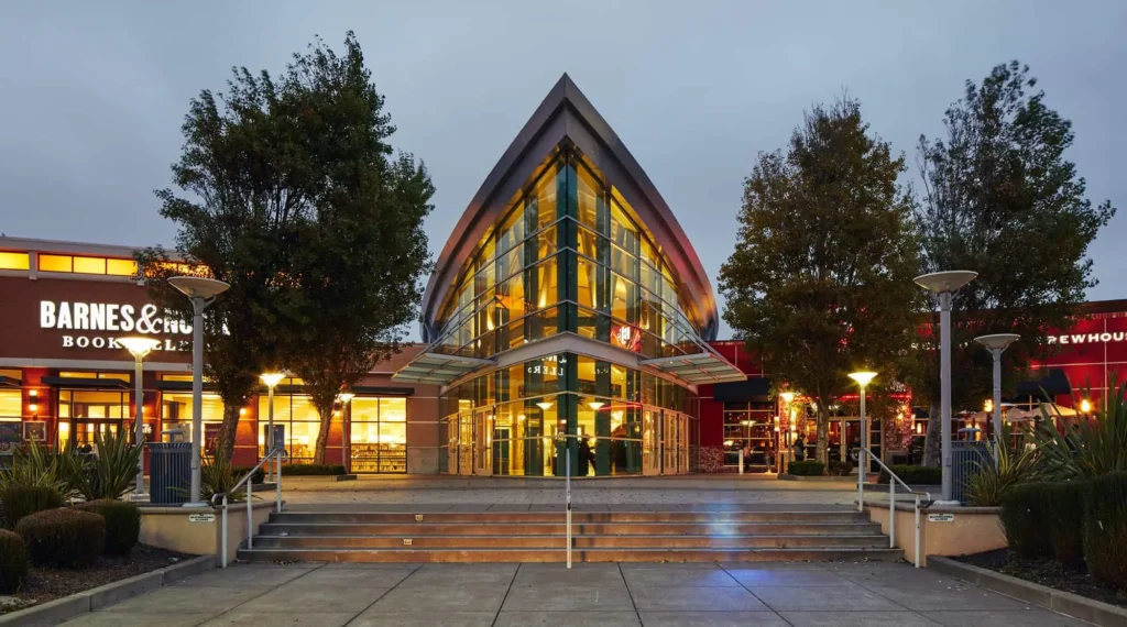 A modern mall building with a sleek glass front and a spacious glass door