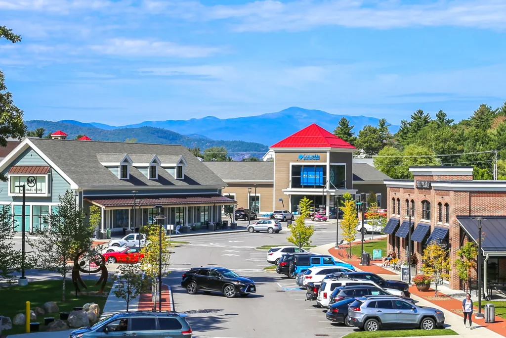 A parking lot with cars and buildings at Tanger Outlets Tilton Mall.