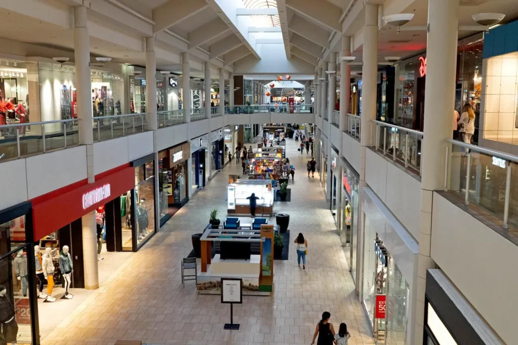 Exterior of Montebello Mall with palm trees and people walking around.