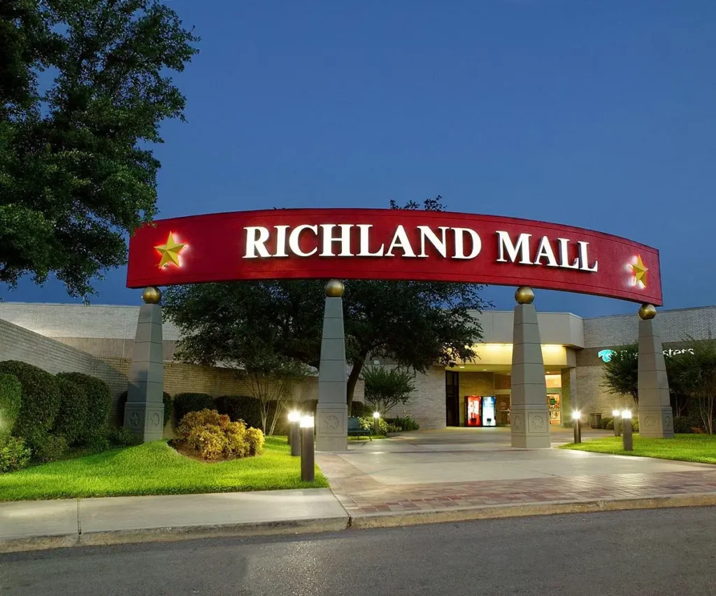 Aerial view of Richland Mall, featuring palm trees and a spacious parking lot.