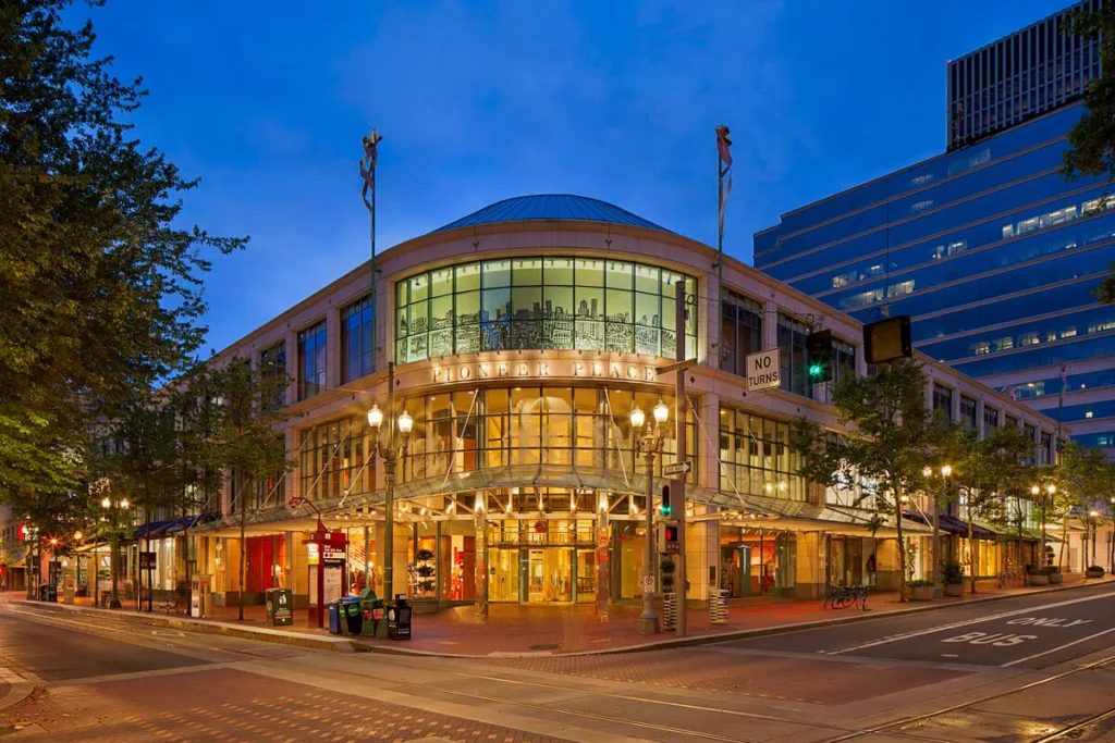 Exterior of Pioneer Place Mall with glass facade and people walking by.