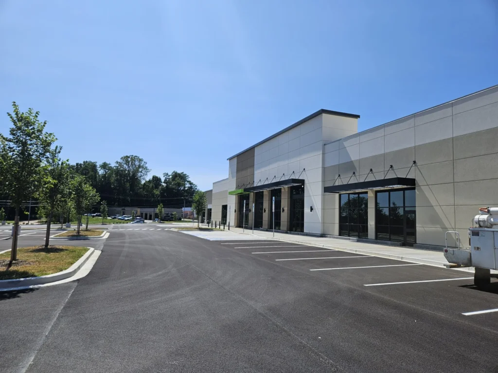 a spacious commercial building surrounded by a parking lot and trees.