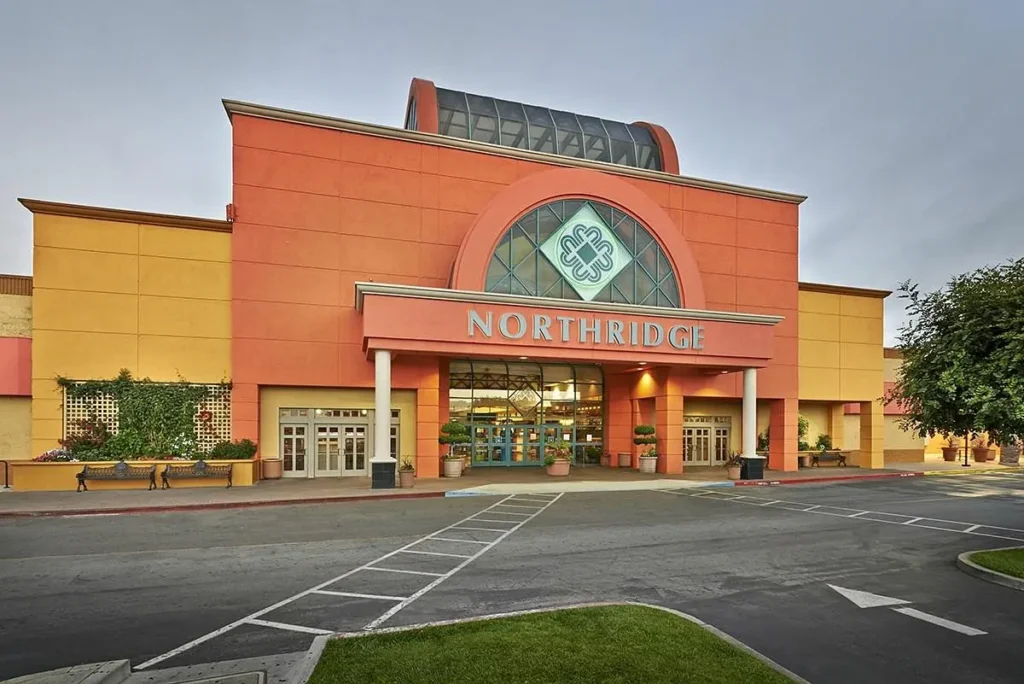 featuring a shopping center surrounded by palm trees and a spacious parking lot.