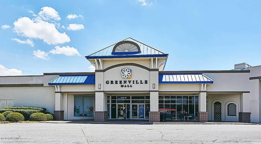 Exterior of Greenville Mall with palm trees and parking lot.