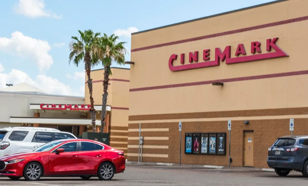 A red car parked in front of a cinema, adding a vibrant touch to the scene.