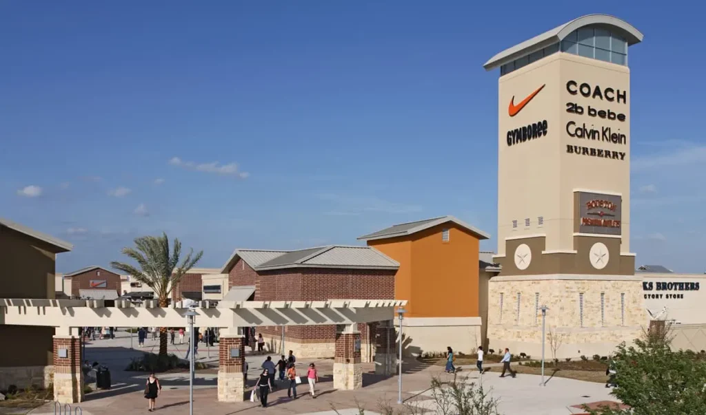 A clock tower and a sign adorn a large building at Houston Premium Outlets Mall.