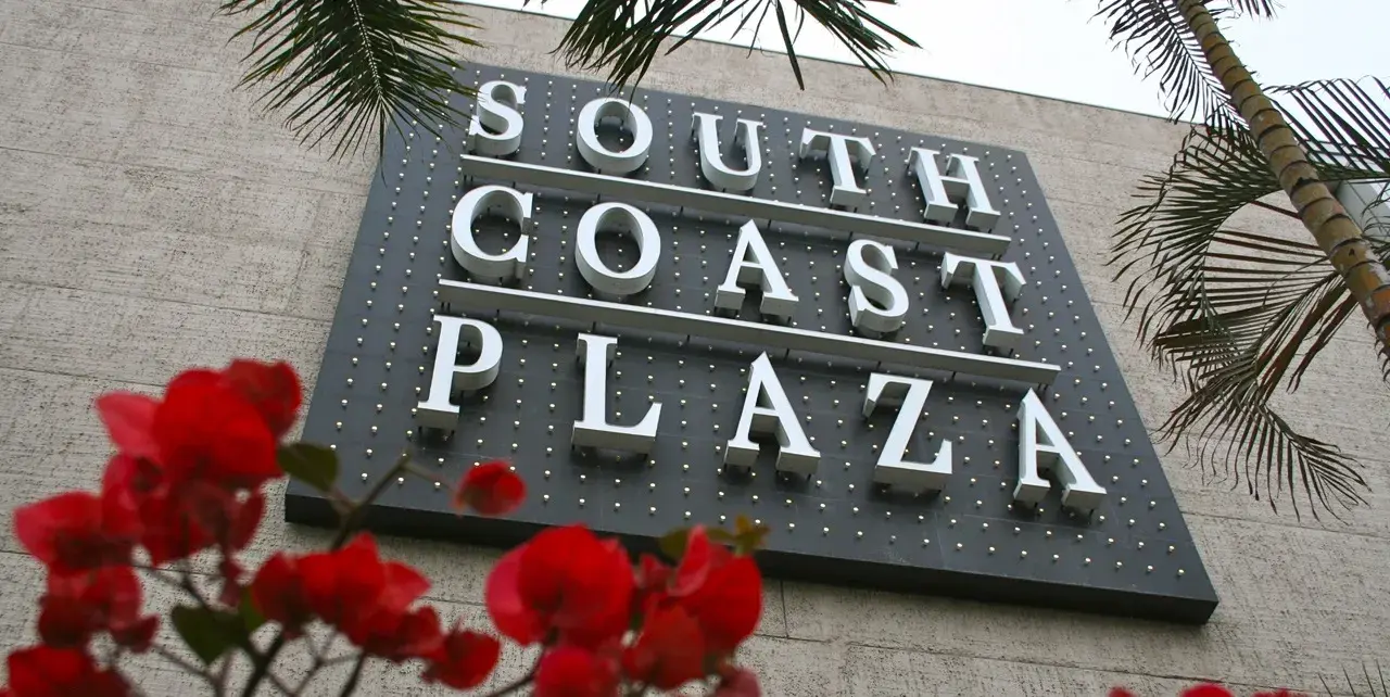 South Coast Plaza Mall sign with red flowers in foreground.