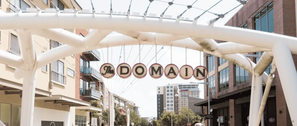 A white archway with a sign reading "downtown" stands at The Domain Mall.