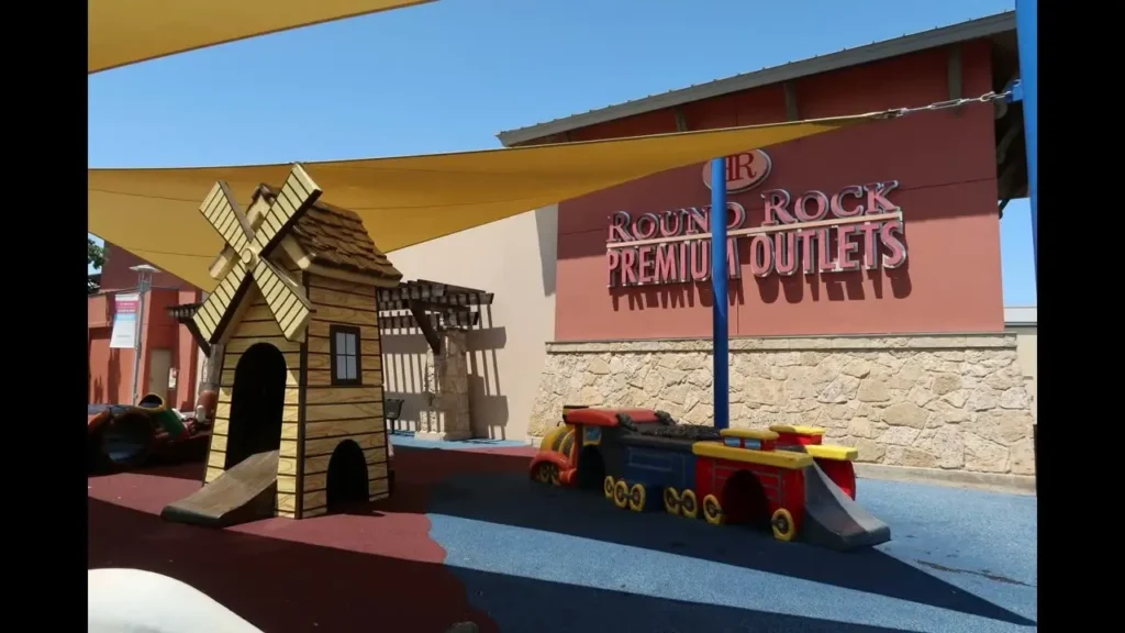 A wooden train and a train at a playground in Round Rock Premium Outlets Mall.