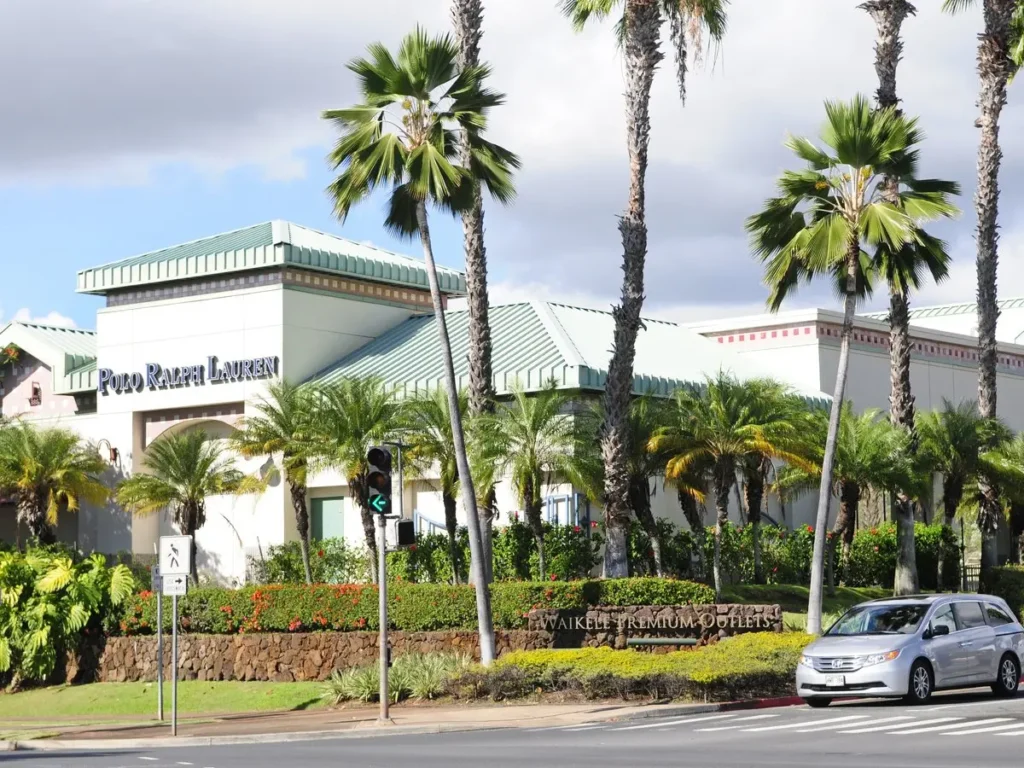 A white car parked in front of Waikele Premium Outlets Mall